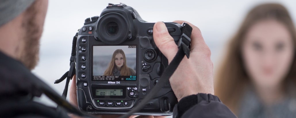 Fotograf fotografiert Fotomodell mit Digitalkamera über Display - Symbolbild Fotometadaten