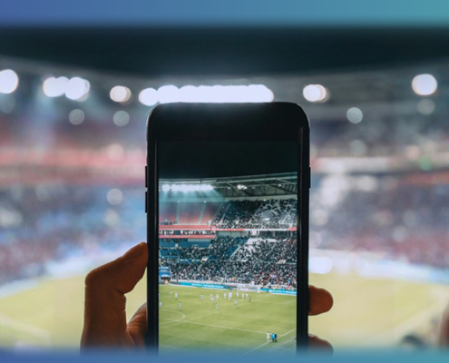 Headergrafik mit Smartphone, mit dem ein Foto im Stadion gemacht wird. Symbolbild für User-generated Content (UGC)